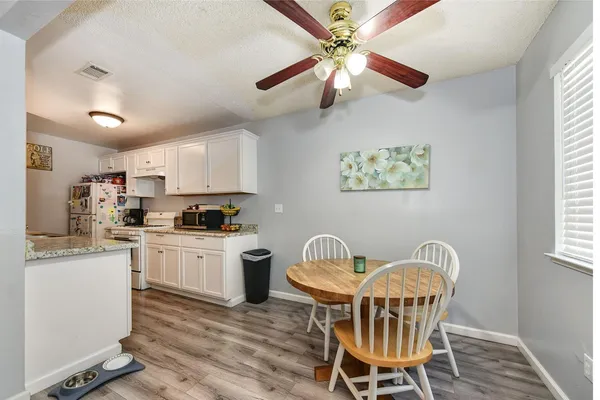 a kitchen with stainless steel appliances granite countertop a dining table chairs refrigerator and sink