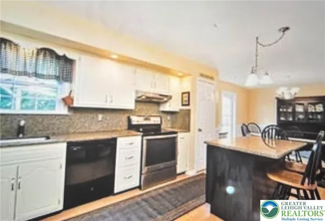 a kitchen with stainless steel appliances a stove a sink dishwasher a refrigerator white cabinets and wooden floor next to a window