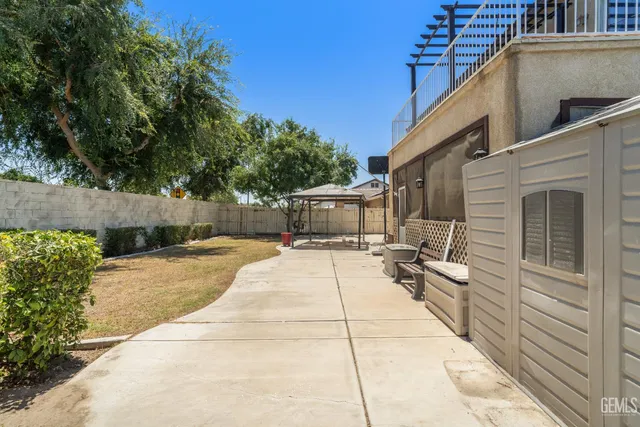 a view of a patio with couches and table and chairs with wooden fence and plants