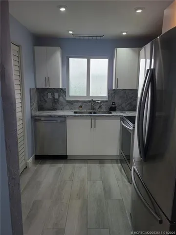 a kitchen with stainless steel appliances granite countertop a sink and a refrigerator