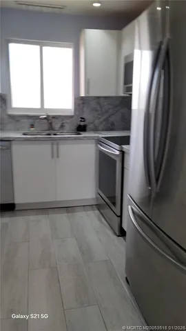 a kitchen with granite countertop a stove a sink and a refrigerator