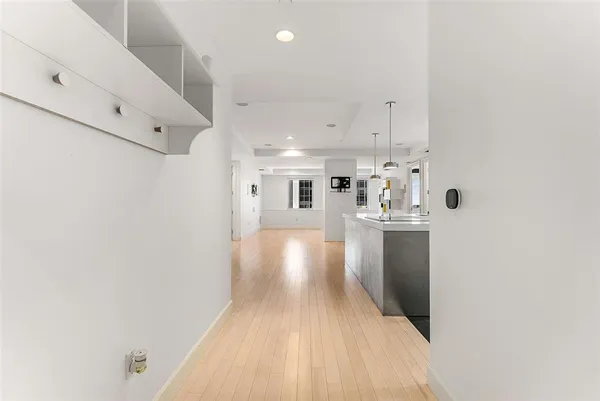 a large white kitchen with a sink a refrigerator and wooden floor