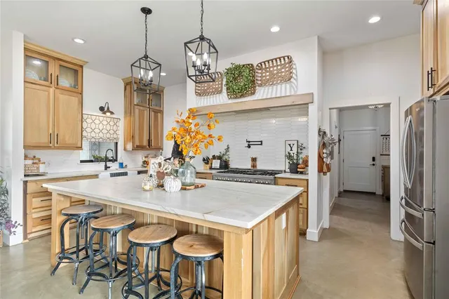 a kitchen with stainless steel appliances kitchen island granite countertop a table chairs and a refrigerator