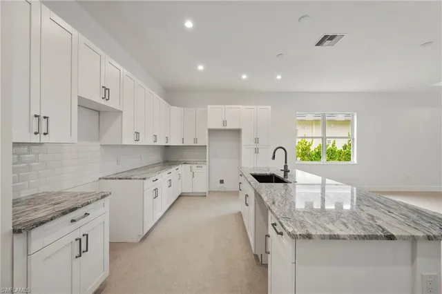 a kitchen with granite countertop a sink stainless steel appliances and white cabinets