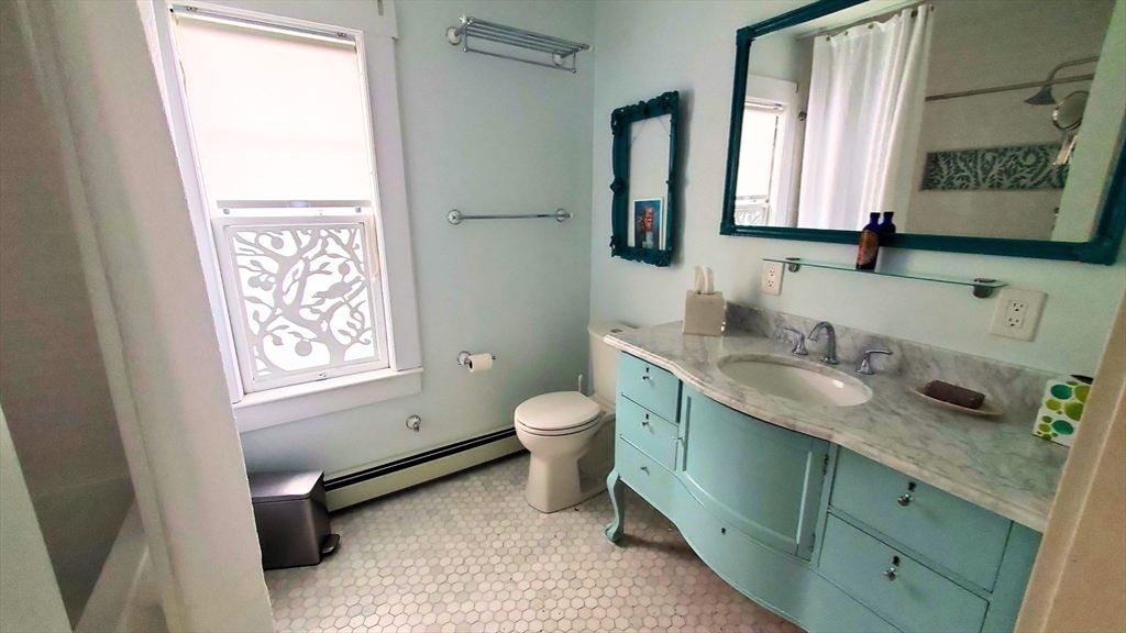 68 Clark Street Worcester, MA 01606 - Photo 32 of 42 a bathroom with a granite countertop toilet a sink and a mirror