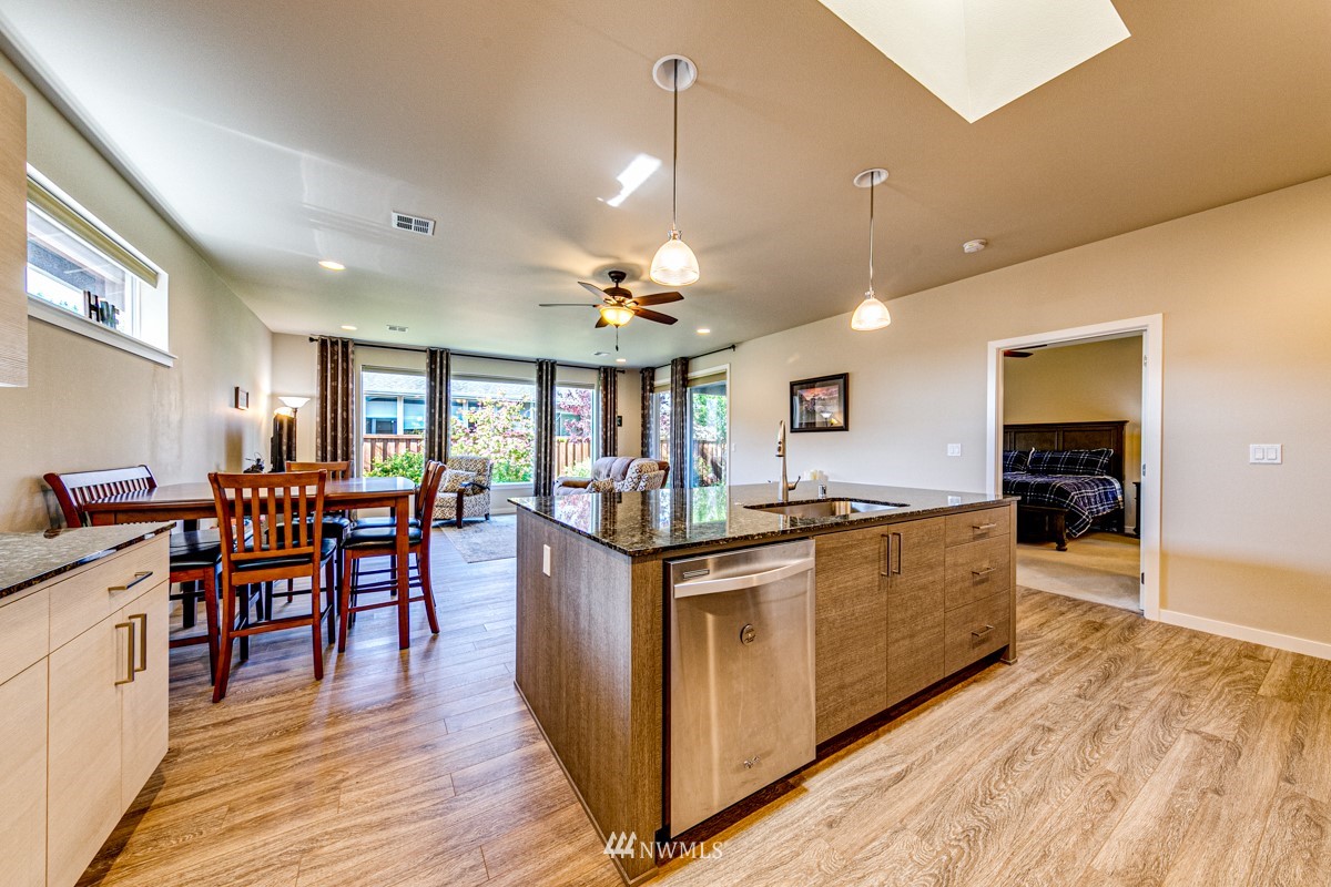 431 Lofgrin Road Sequim, WA 98382 - Photo 13 of 35 a kitchen with stainless steel appliances granite countertop a stove top oven a dining table and chairs with wooden floor