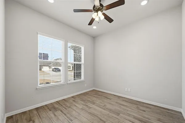 a view of an empty room with a window and wooden floor