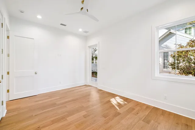an empty room with wooden floor fan and windows