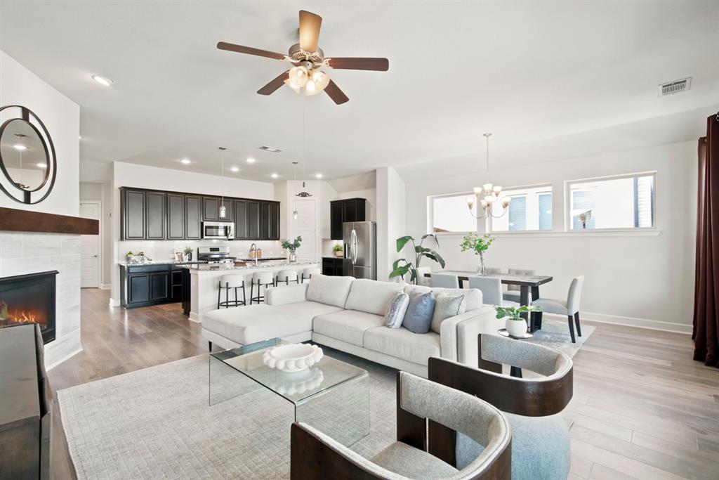 709 Bent Brook Road Oak Point, TX 75068 - Photo 8 of 20 Open-concept living space featuring a light-filled great room with recessed lighting and ceiling fan, complemented by a neutral color palette and wood-finish flooring throughout