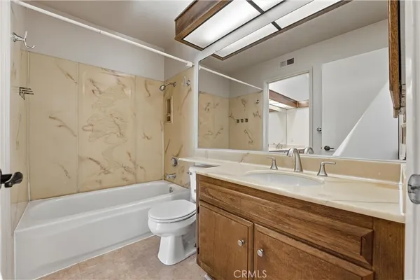 a bathroom with a granite countertop bathtub shower sink vanity mirror and toilet
