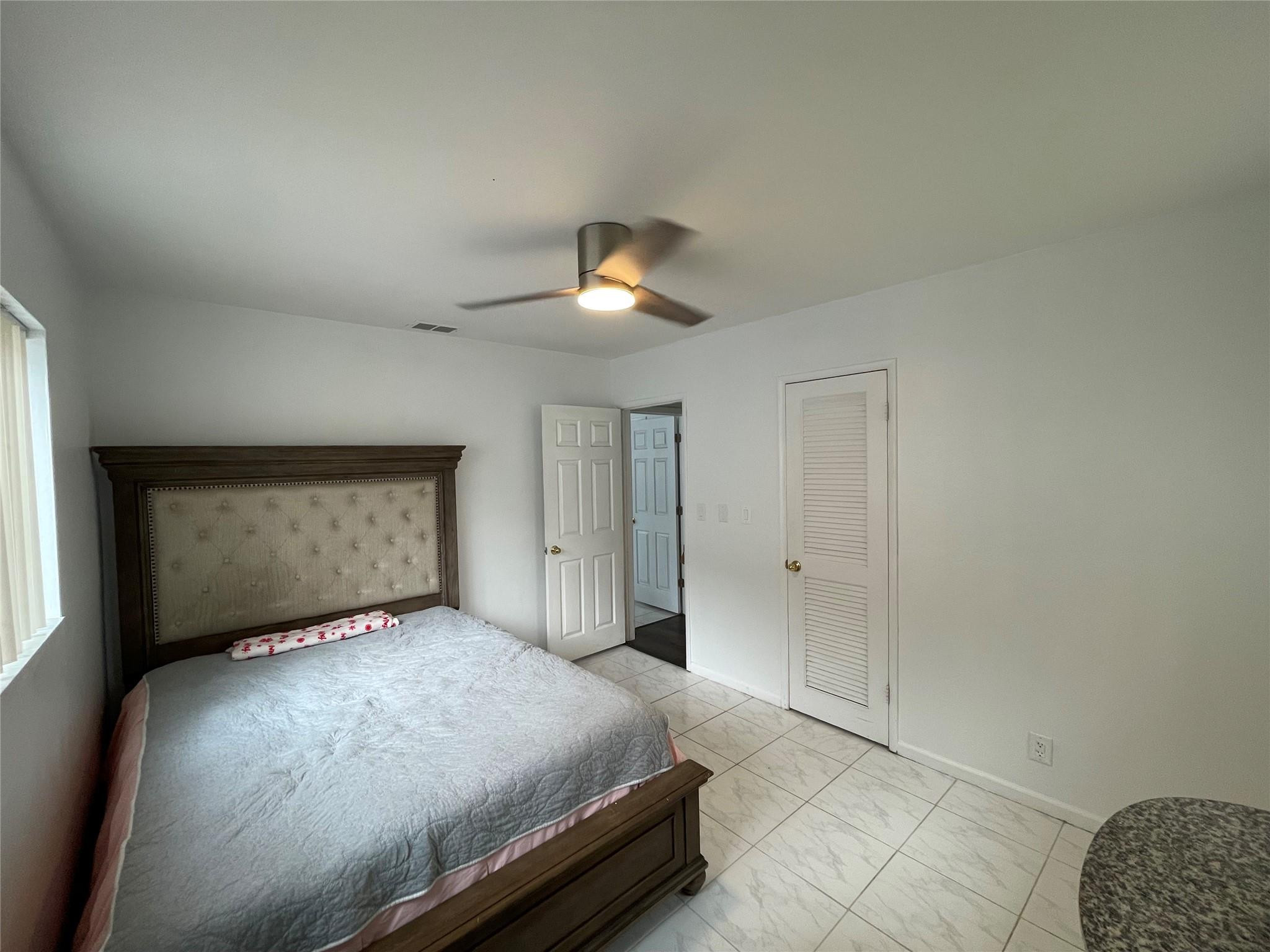 3231 Northeast 27th Terrace Lighthouse Point, FL 33064 - Photo 18 of 30 a bedroom with a bed and a chandelier
