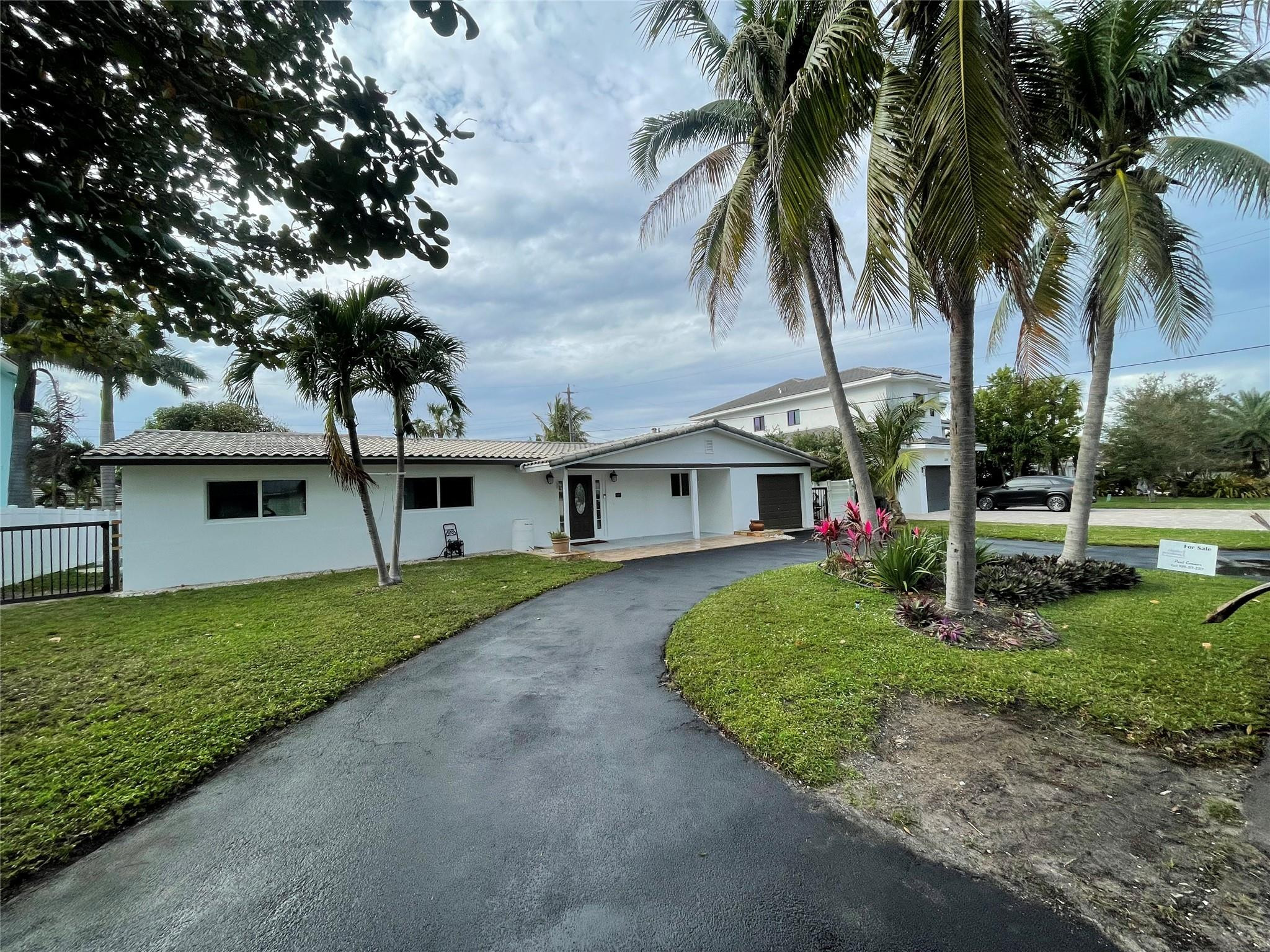 3231 Northeast 27th Terrace Lighthouse Point, FL 33064 - Photo 3 of 30 a view of a house with a yard and palm trees