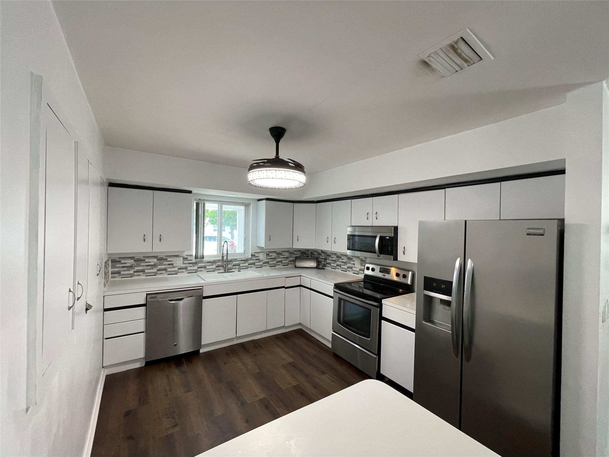 3231 Northeast 27th Terrace Lighthouse Point, FL 33064 - Photo 7 of 30 a kitchen with stainless steel appliances a sink stove refrigerator and cabinets