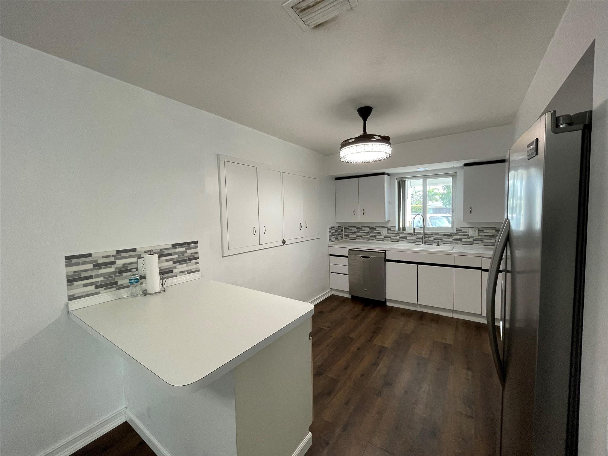 3231 Northeast 27th Terrace Lighthouse Point, FL 33064 - Photo 8 of 30 a kitchen with a refrigerator a sink cabinets and wooden floor