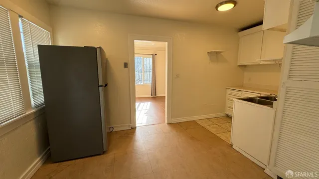 a view of a refrigerator in kitchen and an empty room