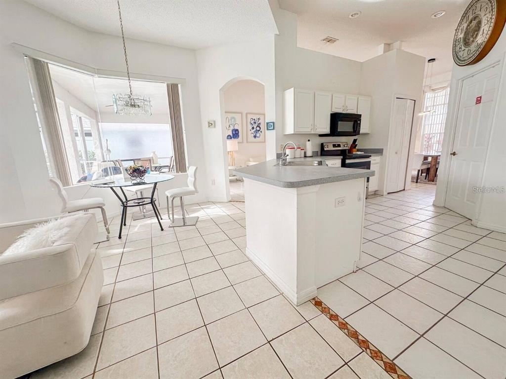 344 Grosvenor Loop Davenport, FL 33897 - Photo 7 of 27 a kitchen with stainless steel appliances a stove a sink and white cabinets with wooden floor
