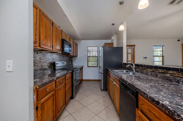 a kitchen with stainless steel appliances granite countertop a stove a sink and a refrigerator