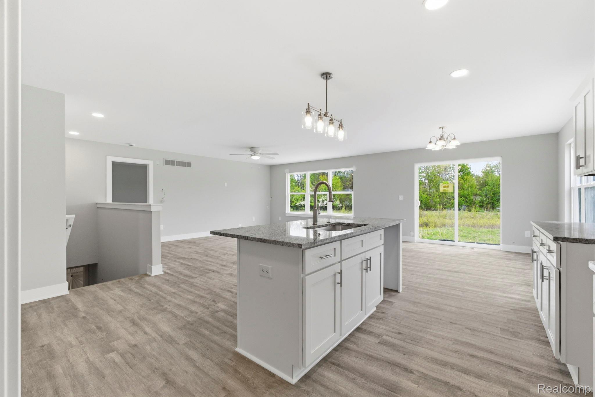 2281 Baltimore Davison, MI 48423 - Photo 26 of 26 Kitchen featuring dark stone counters, a kitchen island with sink, open floor plan, and white cabinetry