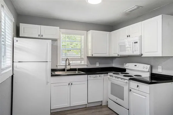 a kitchen with granite countertop white cabinets and refrigerator