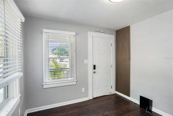 a view of an empty room with wooden floor and a window