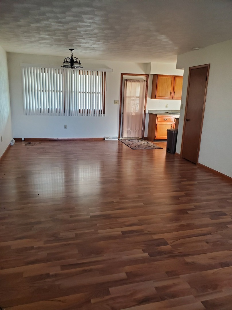 730 North 2853rd Road Utica, IL 61373 - Photo 2 of 23 an empty room with wooden floor and windows