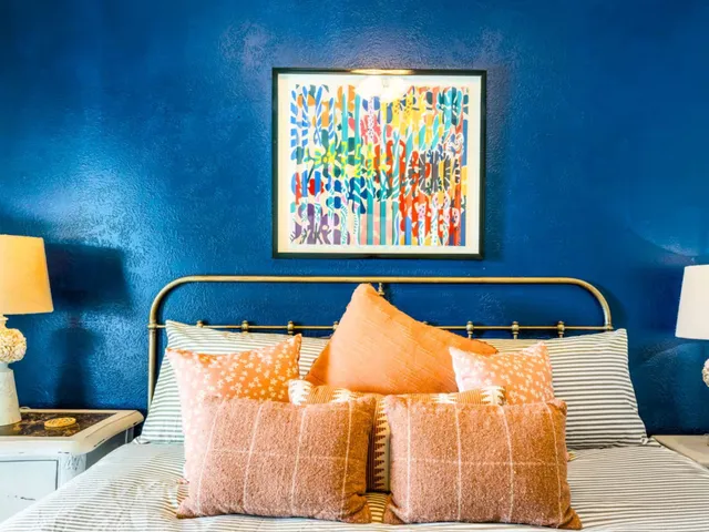 a bedroom with a bed and painting on the wall