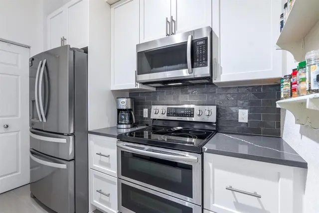 a kitchen with stainless steel appliances white cabinets a stove and a microwave