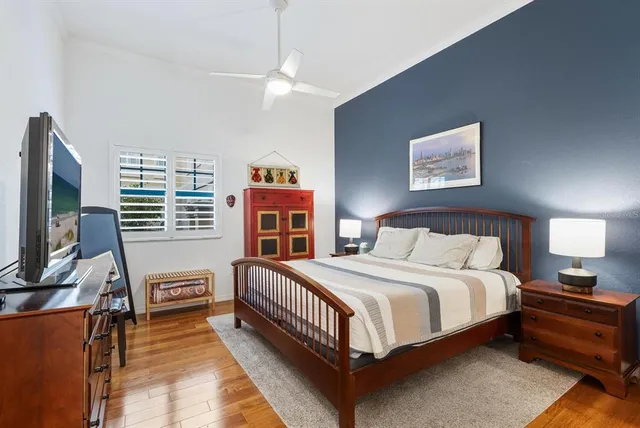 a bedroom with a bed next to a window with a flat tv screen