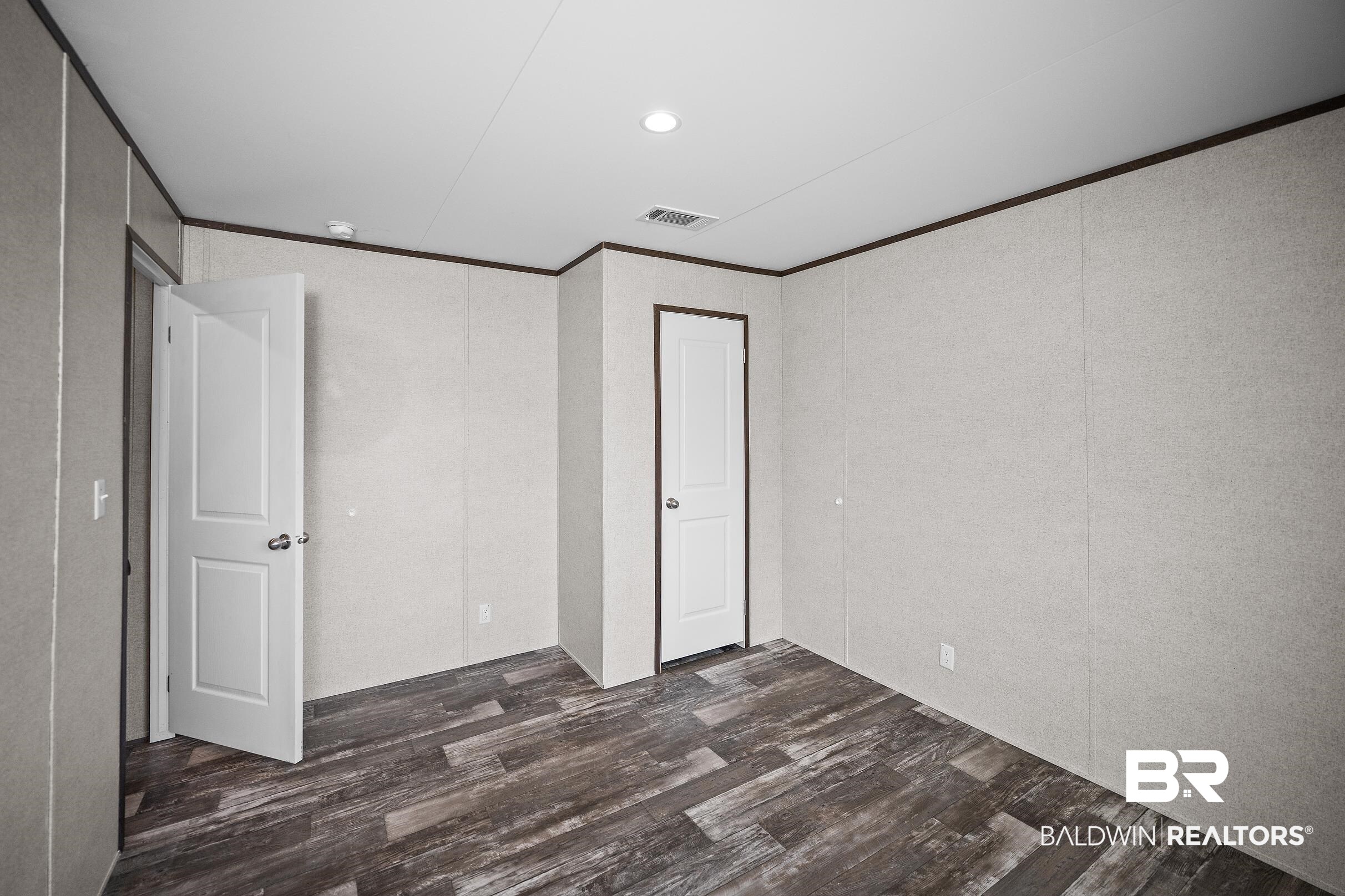 21601 Westside Loop Silverhill, AL 36576 - Photo 35 of 42 Interior room featuring dark wood-finish flooring, light textured wall panels, white two-panel doors with brushed nickel hardware, and dark trim details
