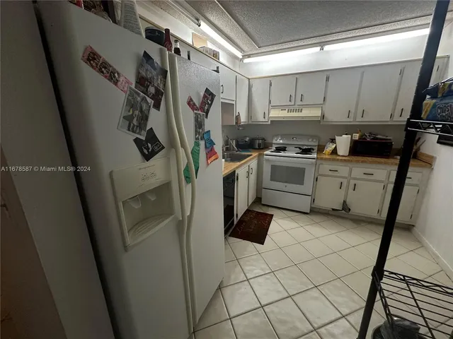 a kitchen with a refrigerator and white cabinets