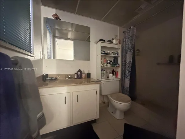 a bathroom with a granite countertop sink a toilet and a shower