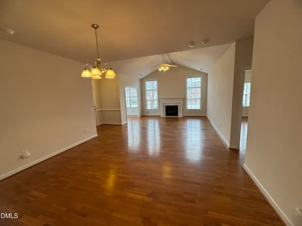 an empty room with wooden floor fireplace and windows
