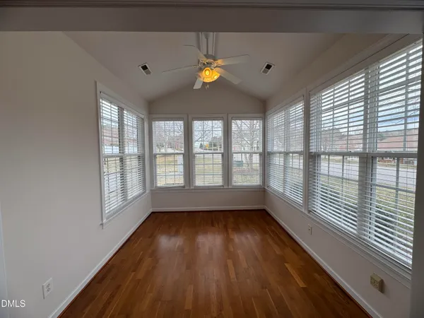a view of empty room with wooden floor and fan