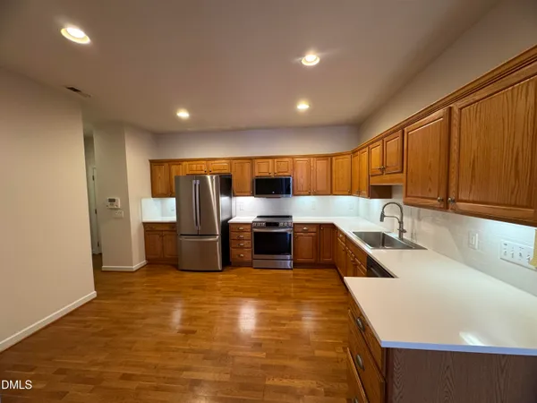 a large kitchen with stainless steel appliances wooden cabinets a sink and a stove