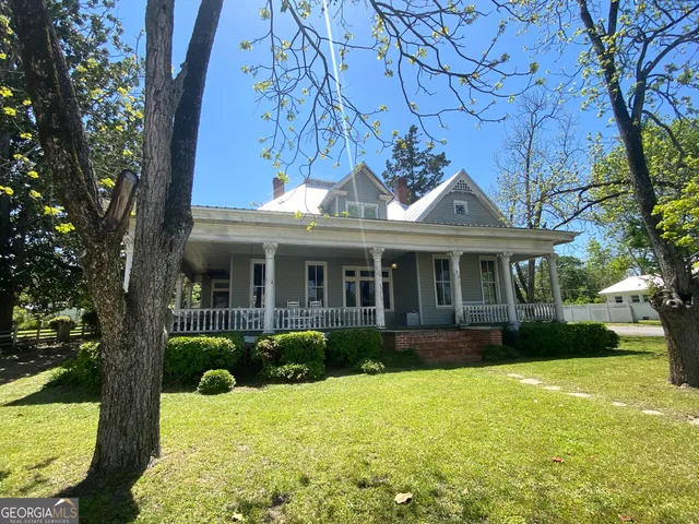 a view of a house with a yard and large tree