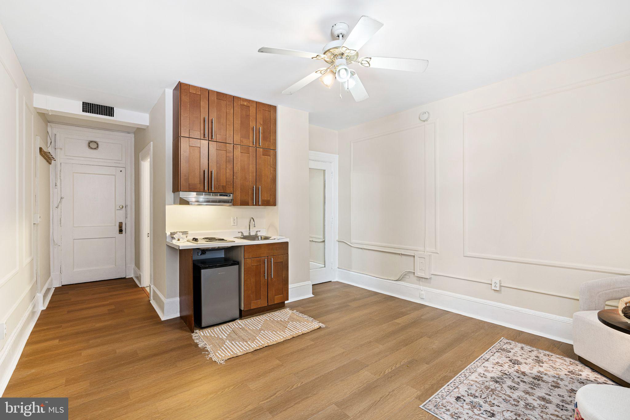 1324 Locust Street, Unit 717 Philadelphia, PA 19107 - Photo 2 of 12 a large white kitchen with kitchen island a stove a sink and a refrigerator