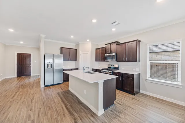 a kitchen with stainless steel appliances granite countertop a stove top oven a sink dishwasher a refrigerator and a microwave oven with wooden floor