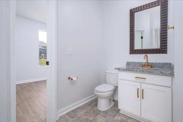 a bathroom with a granite countertop toilet sink and mirror