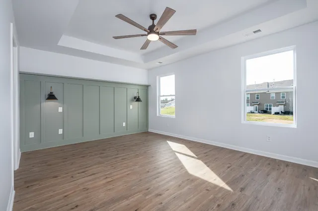 a view of an empty room with window and wooden floor