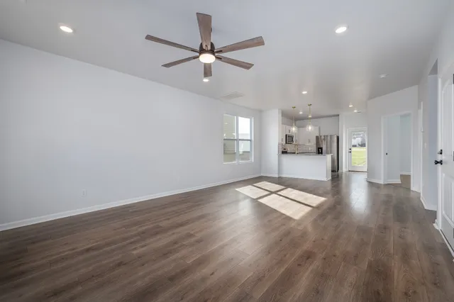 a view of empty room with wooden floor and window