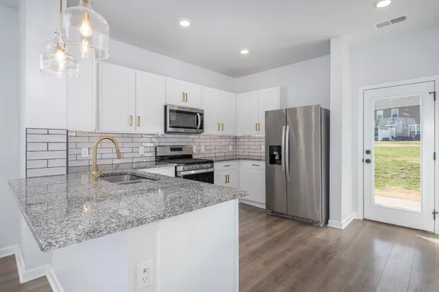 a kitchen with granite countertop a refrigerator a sink a stove a microwave and island