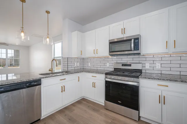 a kitchen with granite countertop a stove sink and microwave