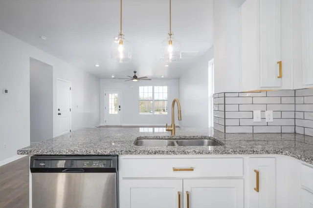 a kitchen with kitchen island granite countertop a sink a counter space and appliances