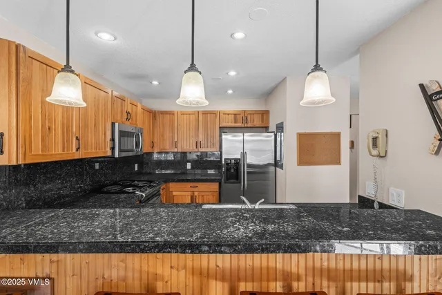 a large kitchen with kitchen island granite countertop a sink a counter space and stainless steel appliances
