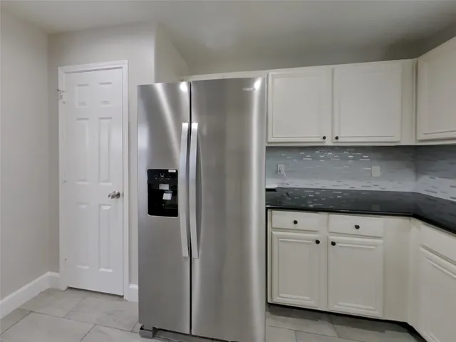 a kitchen with white cabinets and refrigerator