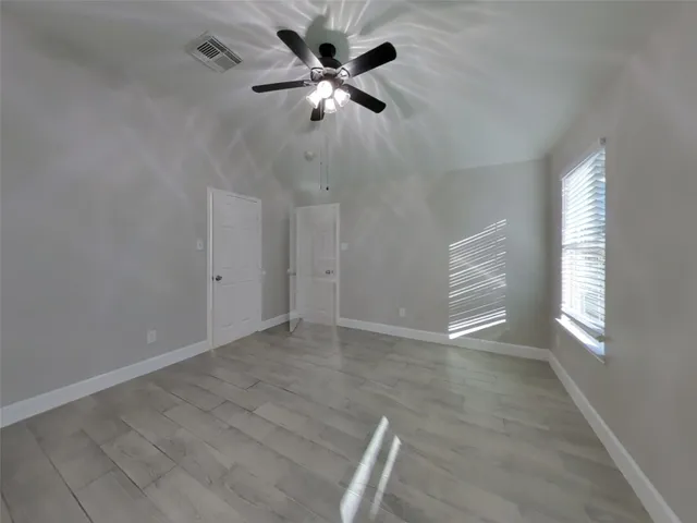 an empty room with windows and fan