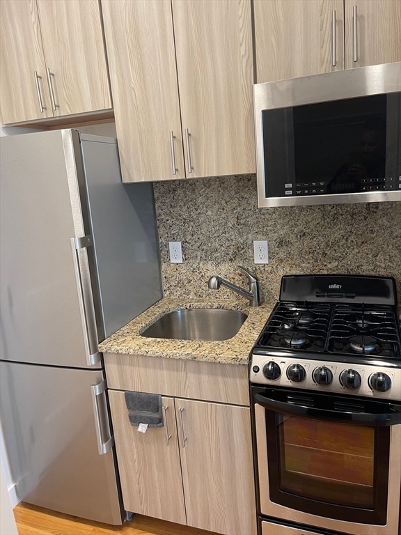 16 5th Street, Unit 31 Chelsea, MA 02150 - Photo 4 of 25 a kitchen with granite countertop a stove and a microwave