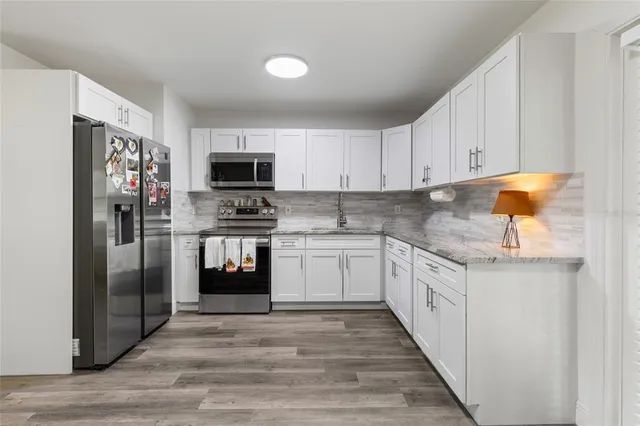 a kitchen with granite countertop a refrigerator and a stove top oven