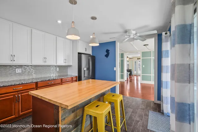 a kitchen with stainless steel appliances granite countertop a refrigerator a sink dishwasher and white cabinets with wooden floor