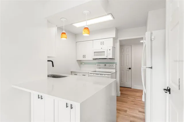 a kitchen with a sink a stove a refrigerator and white cabinets